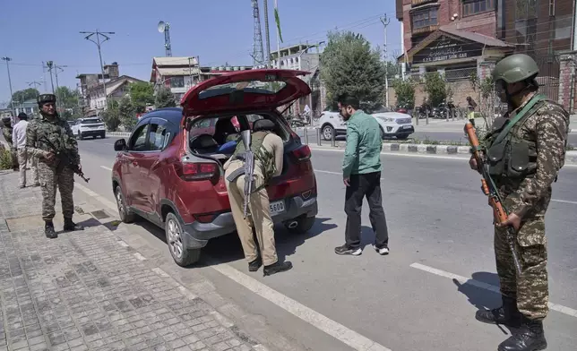 A policeman, center, checks a vehicle as paramilitary soldiers stand guard at a temporary checkpoint in Srinagar, Indian controlled Kashmir, Wednesday, April 30, 2025. (AP Photo/Dar Yasin)