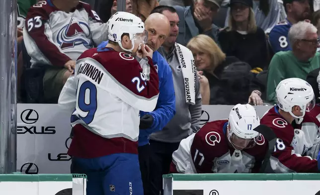 Colorado Avalanche center Nathan MacKinnon (29) is attended to by medical staff after he was high-sticked during a first-round NHL hockey playoff game against the Dallas Stars in Dallas, Saturday, April 19, 2025. (AP Photo/Gareth Patterson)