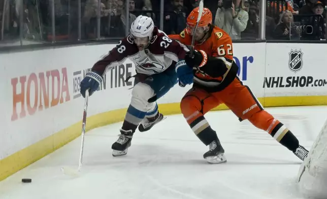Colorado Avalanche left wing Miles Wood (28) reaches for the puck with pressure from Anaheim Ducks center Nikita Nesterenko (62) during the first period of an NHL hockey game in Anaheim, Calif., Sunday, April 13, 2025. (AP Photo/Alex Gallardo)