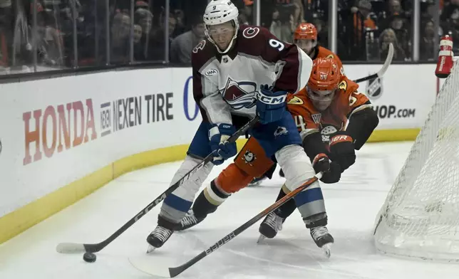 Colorado Avalanche center T.J. Tynan (9) controls the puck with pressure from Anaheim Ducks right wing Sam Colangelo (64) during the first period of an NHL hockey game in Anaheim, Calif., Sunday, April 13, 2025. (AP Photo/Alex Gallardo)