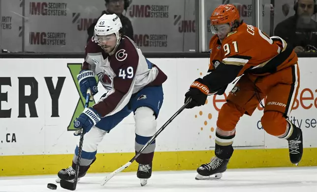 Colorado Avalanche defenseman Samuel Girard (49) controls the puck with Anaheim Ducks center Leo Carlsson (91) in pursuit during the first period of an NHL hockey game in Anaheim, Calif., Sunday, April 13, 2025. (AP Photo/Alex Gallardo)