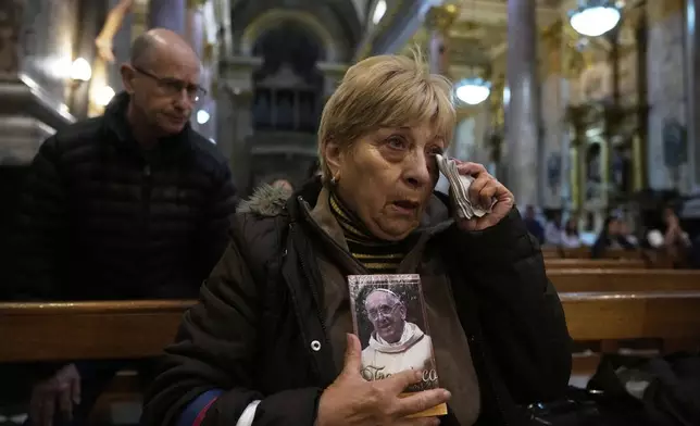 Maria Teresa Delgado holds a portrait of the late Pope Francis during Mass at the Basílica de San José de Flores, where he worshipped as a youth, following the Vatican's announcement of his death in Buenos Aires, Argentina, Monday, April 21, 2025. (AP Photo/Gustavo Garello)
