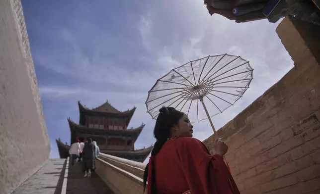 A woman is dressed in traditional costume as she and visitors tour Jiayu Pass, a strategic point of the Great Wall of China along the ancient "Silk Road," near the city of Jiayuguan in China's northwestern Gansu province, Tuesday, April 22, 2025. (AP Photo/Andy Wong)