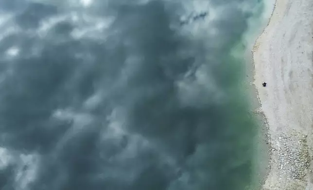 Clouds are reflected in the water of lake 'Walchensee' during low water near Garmisch-Partenkirchen, Germany, Tuesday, April 22, 2025. (AP Photo/Matthias Schrader)