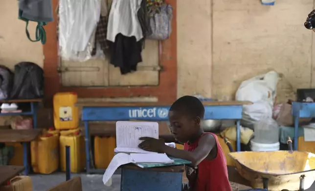 A child does homework at a school operating as a shelter for those fleeing gang violence in Port-au-Prince, Haiti, Monday, April 21, 2025. (AP Photo/Odelyn Joseph)