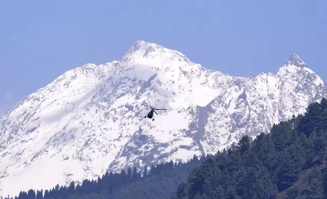 A snow-clad mountain peak rises behind an army helicopter patrolling above the valley the morning after militants indiscriminately opened fire on tourists near Pahalgam in Indian controlled Kashmir, Wednesday, April 23, 2025. (AP Photo/Dar Yasin)
