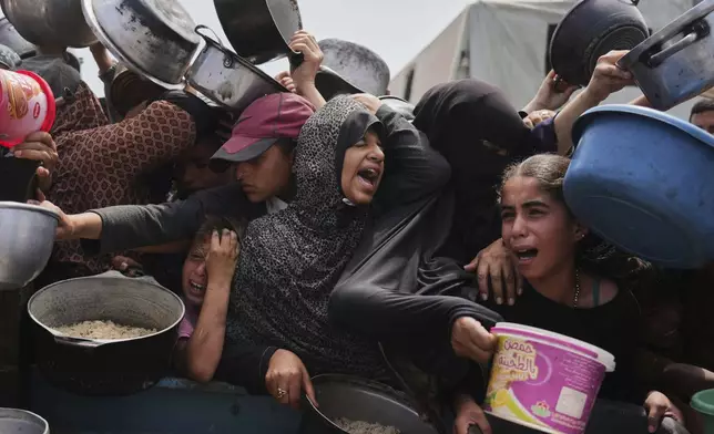 Palestinian children receive donated food at a distribution center in Khan Younis, Gaza Strip, Monday, April 21, 2025. (AP Photo/Abdel Kareem Hana)