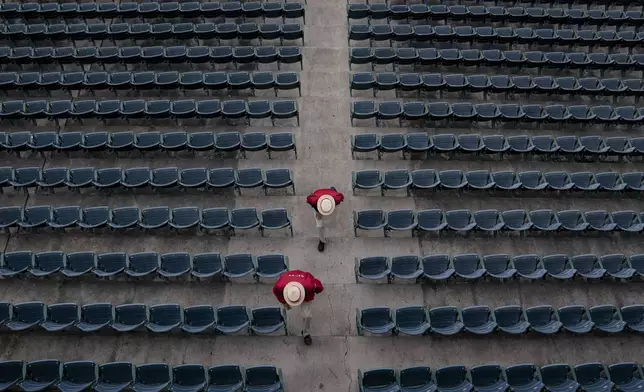 Stadium ushers walk through seats before a baseball game between the Pittsburgh Pirates and the Los Angeles Angels in Anaheim, Calif., Wednesday, April 23, 2025. (AP Photo/Eric Thayer)