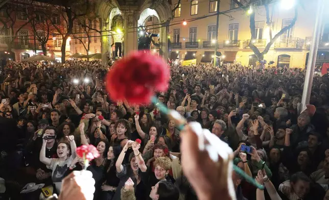 Thousands of people sing the folk song Grandola, Vila Morena, in the first minutes of Friday, April 25, 2025, at the Carmo square in Lisbon, celebrating the anniversary of the April 25, 1974, Carnation Revolution that restored democracy in Portugal. (AP Photo/Armando Franca)