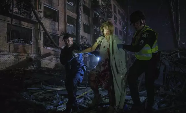 Police officers help an injured woman leave her house, which was damaged by a Russian airstrike, in a residential neighbourhood in Kyiv, Ukraine, on Thursday, April 24, 2025. (AP Photo/Evgeniy Maloletka)