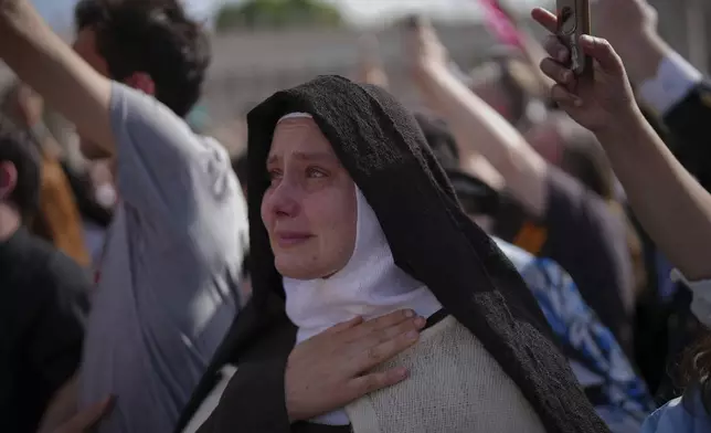 A nun cries as the body of Pope Francis is carried into St. Peter's Basilica at the Vatican, Wednesday, April 23, 2025, where he will lie in state for three days. (AP Photo/Emilio Morenatti)