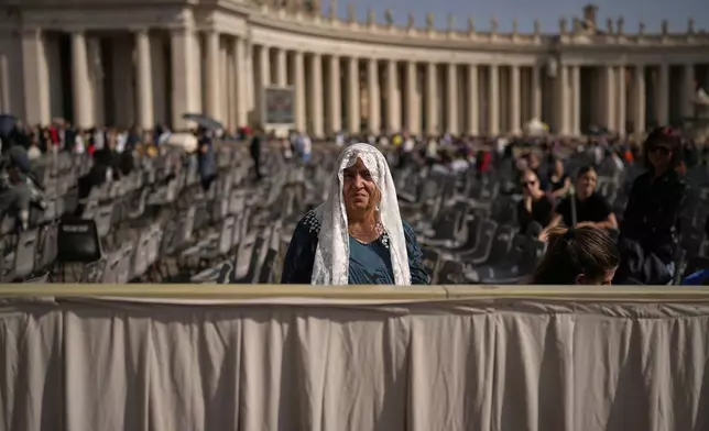 A woman sits in St. Peter's Square as people wait to pay their respects to the late Pope Francis, who will lie in state at St. Peter's Basilica for three days, at the Vatican, Wednesday, April 23, 2025. (AP Photo/Andreea Alexandru)