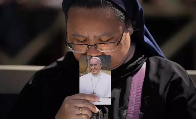 A nun holds a photo of Pope Francis while attending his funeral in St. Peter's Square at the Vatican, Saturday, April 26, 2025. (AP Photo/Andreea Alexandru)
