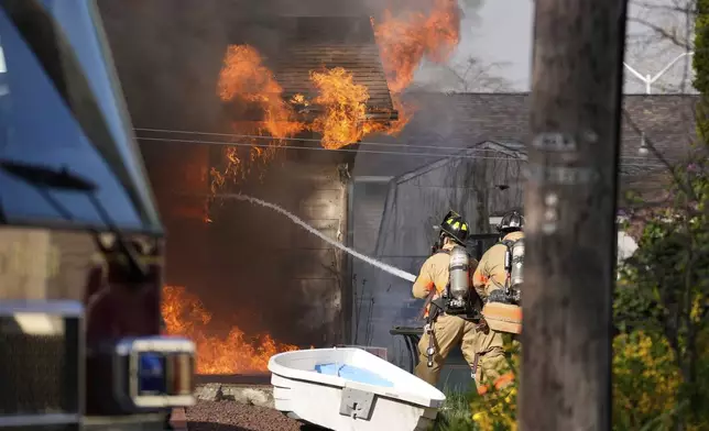Firefighters battle a house fire Wednesday, April 23, 2025, in Lacey Township, N.J. (AP Photo/Matt Slocum)