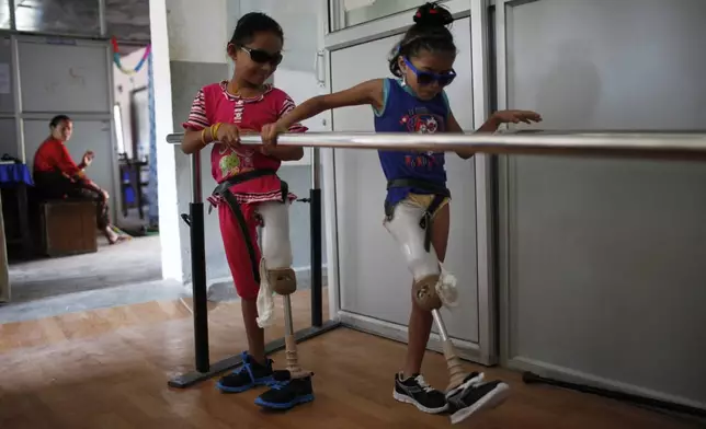 Khendo Tamang, left, and Nirmala Pariyar try out their prosthetic legs for the first time at a rehabilitation center in Kathmandu, Nepal, Aug. 19, 2015. (AP Photo/Niranjan Shrestha)