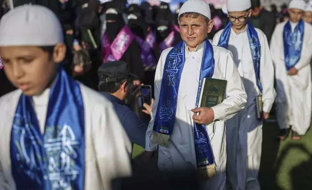 A boy holds a copy of the Holy Quran as he stands during a ceremony honouring more than a thousand boys and girls for memorising the Islamic holy book while studying in the network of religious schools Dar Al-Wahi that operate under the supervision the government, at the municipal stadium in Idlib, Syria, Saturday April 26, 2025. (AP Photo/Ghaith Alsayed)