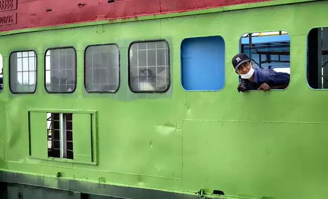 A ferry workers looks out from his ship along the Saigon River on Saturday, April 26, 2025 in Ho Chi Minh City, Vietnam.. (AP Photo/Richard Vogel)