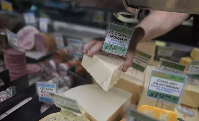Jeff Gibbs, owner of Gibbs Cheese, reaches for Pecorino Romano cheese imported from Sardinia, Italy, at his shop in Findlay Market, Thursday, April 3, 2025, in Cincinnati. (AP Photo/Carolyn Kaster)