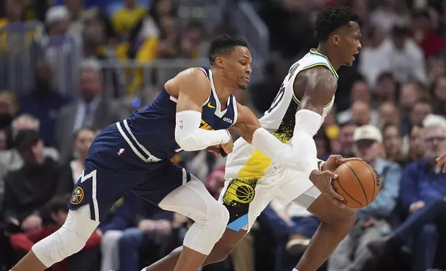 Denver Nuggets guard Russell Westbrook, left, tries to steal the ball from Indiana Pacers guard Bennedict Mathurin in the first half of an NBA basketball game Sunday, April 6, 2025, in Denver. (AP Photo/David Zalubowski)