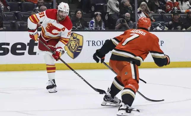 Calgary Flames center Nazem Kadri, left, controls the puck away from Anaheim Ducks defenseman Radko Gudas during the second period of an NHL hockey game, Wednesday, April 9, 2025, in Anaheim, Calif. (AP Photo/Etienne Laurent)