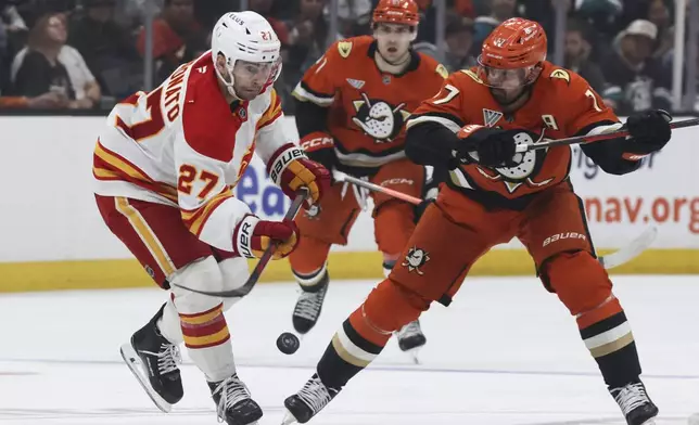 Calgary Flames winger Matt Coronato, left, controls the puck away from Anaheim Ducks winger Frank Vatrano during the second period of an NHL hockey game, Wednesday, April 9, 2025, in Anaheim, Calif. (AP Photo/Etienne Laurent)