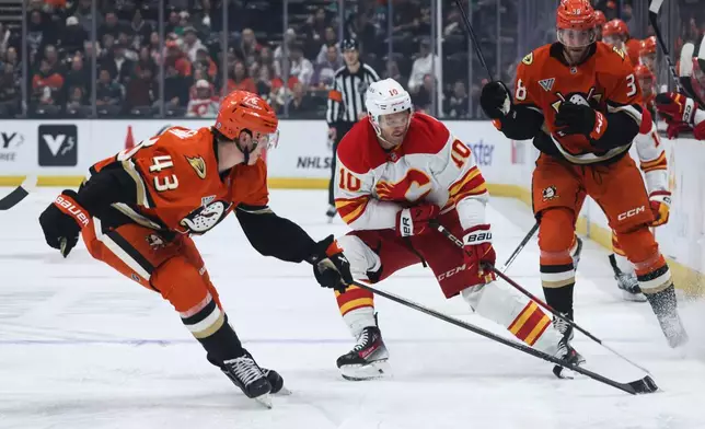 Calgary Flames winger Jonathan Huberdeau, right, vies for the puck against Anaheim Ducks defenseman Drew Helleson during the second period of an NHL hockey game, Wednesday, April 9, 2025, in Anaheim, Calif. (AP Photo/Etienne Laurent)
