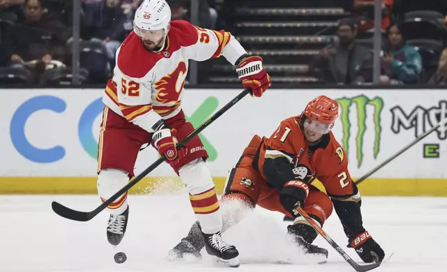 Calgary Flames defenseman MacKenzie Weegar, left, controls the puck away from Anaheim Ducks center Isac Lundestrom during the first period of an NHL hockey game, Wednesday, April 9, 2025, in Anaheim, Calif. (AP Photo/Etienne Laurent)