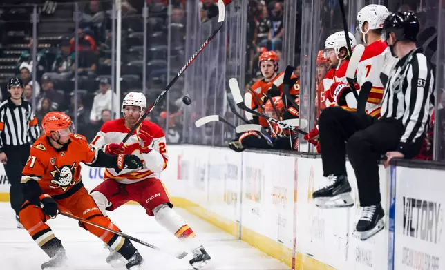 Anaheim Ducks center Isac Lundestrom, left, and Calgary Flames center Kevin Rooney vie for the puck during the second period of an NHL hockey game, Wednesday, April 9, 2025, in Anaheim, Calif. (AP Photo/Etienne Laurent)