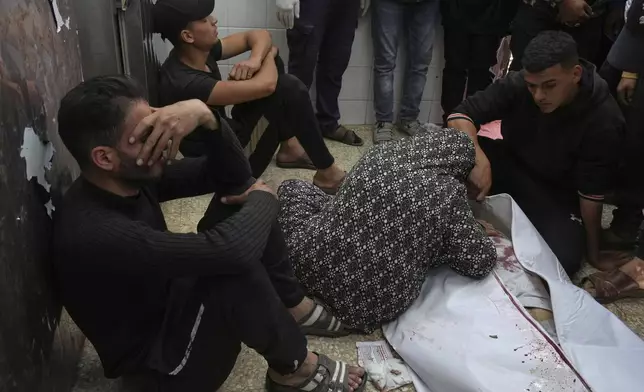 Relatives mourn next to the body of a Palestinian killed in an Israeli airstrike, at the morgue of Al-Aqsa Hospital in Deir al-Balah, central Gaza Strip, Saturday, April 12, 2025. (AP Photo/Abdel Kareem Hana)
