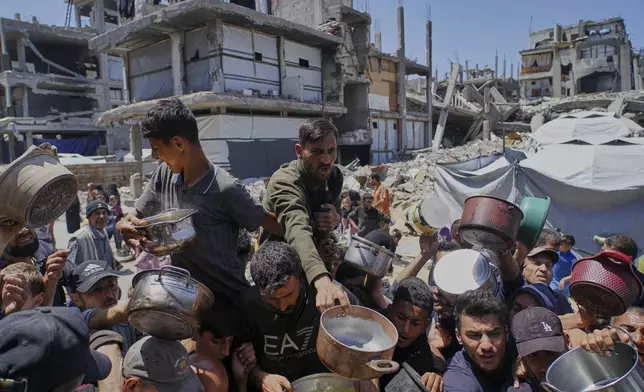 Palestinians receive donated food at a distribution center in Beit Lahia, northern Gaza Strip, Tuesday, April 29, 2025. (AP Photo/Jehad Alshrafi)