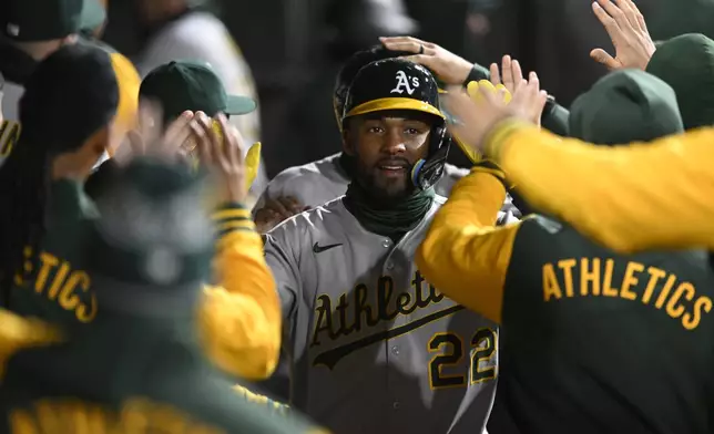 Athletics' Miguel Andujar (22) and JJ Bleday (33) celebrate with teammates in the dugout after scoring on a Gio Urshela two-RBI triple during the sixth inning of a baseball game against the Chicago White Sox, Wednesday, April 16, 2025, in Chicago. (AP Photo/Paul Beaty)