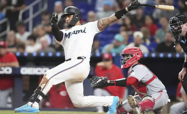 Miami Marlins' Agustin Ramirez, left, follows through on a RBI double to score Eric Wagaman during the sixth inning of a baseball game against the Cincinnati Reds, Tuesday, April 22, 2025, in Miami. (AP Photo/Lynne Sladky)