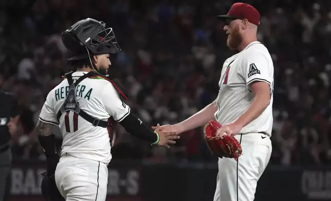Arizona Diamondbacks catcher Jose Herrera (11) and pitcher A.J. Puk celebrate after defeating the Milwaukee Brewers in a baseball game, Sunday, April 13, 2025, in Phoenix. (AP Photo/Rick Scuteri)