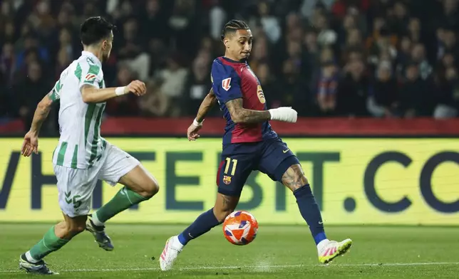 Barcelona's Raphinha, right, dribbles the ball past Betis' Marc Bertra during a Spanish La Liga soccer match between Barcelona and Real Betis at the Lluis Companys Olympic stadium in Barcelona, Spain, Saturday, April 5, 2025. (AP Photo/Joan Monfort)