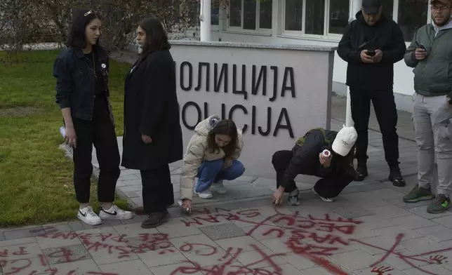People use red spray paint in front of a local police station during an anti-corruption protest led by university students in the southwestern town of Novi Pazar, Serbia, Saturday, April 12, 2025. (AP Photo/Marko Drobnjakovic)