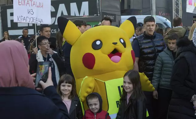 A person dressed in a Pikachu costume poses for photographs with people during an anti-corruption protest led by university students in the southwestern town of Novi Pazar, Serbia, Saturday, April 12, 2025. (AP Photo/Marko Drobnjakovic)