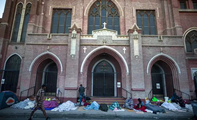 FILE - In this photo taken on Tuesday, May 9, 2023, migrants wake up at the campsite outside Sacred Heart Church in downtown El Paso, Texas. (AP Photo/Andres Leighton, File)