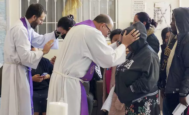 FILE - The Rev. Brian Strassburger, left, and the Rev. Flavio Bravo, right, bless migrants during Mass at the Casa del Migrant shelter in Reynosa, Mexico, on Dec. 15, 2022. (AP Photo/Giovanna Dell'Orto, File)