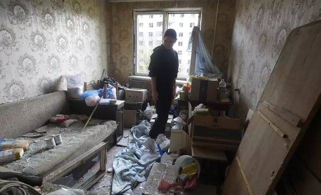A woman stands inside her apartment damaged by a Russian strike in Kharkiv, Ukraine, Friday April 18, 2025. (AP Photo/Andrii Marienko)