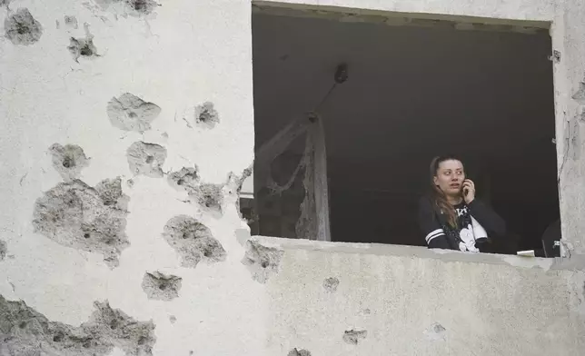 A woman looks though the window of her damaged apartment following a Russian strike in Kharkiv, Ukraine, Friday April 18, 2025. (AP Photo/Andrii Marienko)