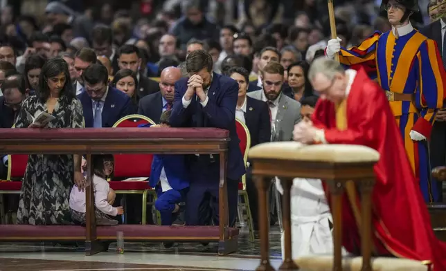 U.S. Vice President JD Vance, and his wife Usha Vance, left, with their daughter Mirabel attend a Good Friday service led by Cardinal Claudio Gugerotti, right, inside St. Peter's Basilica at the Vatican, Friday, April 18, 2025. (AP Photo/Alessandra Tarantino)