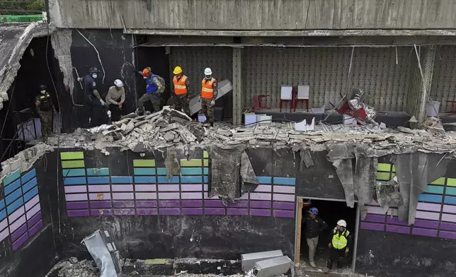 Rescue workers stand at site of the Jet Set nightclub days after its roof collapsed during a concert, killing more than 200 people in Santo Domingo, Dominican Republic, Thursday, April 10, 2025. (AP Photo/Matias Delacroix)