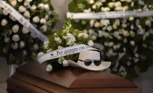 The hat and sunglasses of Dominican singer Rubby Perez, who died in the roof collapse at the Jet Set nightclub during his merengue concert, sit on his casket during his wake at the Eduardo Brito National Theater in Santo Domingo, Dominican Republic, Thursday, April 10, 2025. (AP Photo/Matias Delacroix)