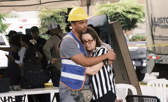 A rescue worker comforts a woman during the search for survivors at the Jet Set nightclub after its roof collapsed two nights prior during a merengue concert in Santo Domingo, Dominican Republic, Wednesday, April 9, 2025. (AP Photo/Ricardo Hernandez)