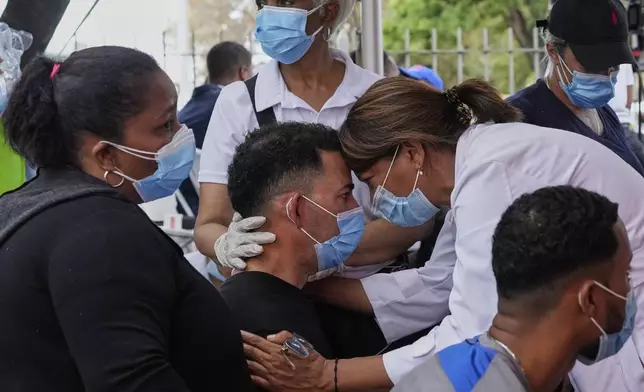 A person is comforted before identifying the body of a family member who died at the Jet Set nightclub, days after its roof collapsed during a concert and killed more than 200 people, outside the National Institute of Forensic Pathology in Santo Domingo, Dominican Republic, Thursday, April 10, 2025. (AP Photo/Matias Delacroix)