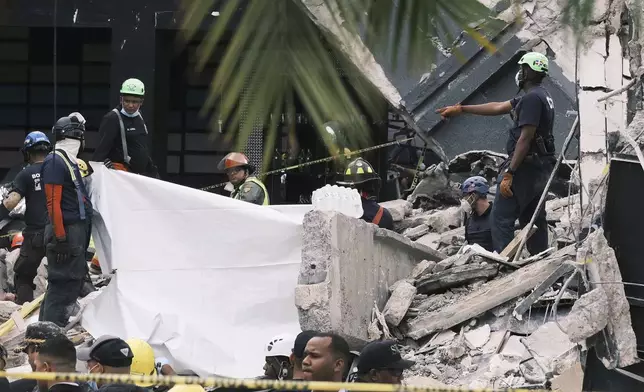 Rescue workers use sheets as they recover bodies from the rubble at the Jet Set nightclub after its roof collapsed two nights prior during a merengue concert in Santo Domingo, Dominican Republic, Wednesday, April 9, 2025. (AP Photo/Ricardo Hernandez)