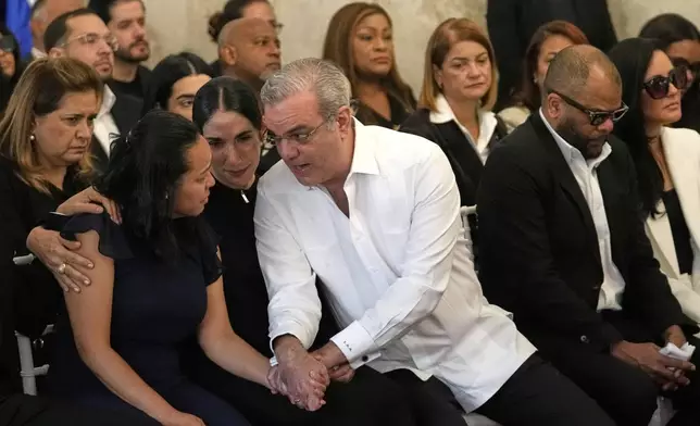 Dominican Republic President Luis Abinader, center right, and his wife Raquel Arbaje Soni speak with the family of Dominican singer Rubby Perez who died in the roof collapse at the Jet Set nightclub while performing in concert, during the wake at the Eduardo Brito National Theater in Santo Domingo, Dominican Republic, Thursday, April 10, 2025. (AP Photo/Matias Delacroix)
