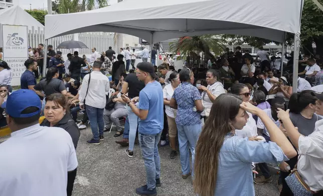 Family members wait to identify the remains of their loved who died when the roof collapsed at the Jet Set nightclub during a merengue concert, in a parking lot of the National Institute of Forensic Pathology in Santo Domingo, Dominican Republic, Wednesday, April 9, 2025, (AP Photo/Marvin Del Cid)