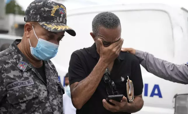 Carlos Severino, whose three children died in the Jet Set nightclub when a roof collapsed during a merengue concert, is consoled as he waits to receive the remains of his children, outside the morgue of the National Institute of Forensic Pathology in Santo Domingo, Dominican Republic, Friday, April 11, 2025. (AP Photo/Matias Delacroix)