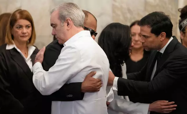 Dominican Republic President Luis Abinader, front, consoles the family of Dominican singer Rubby Perez who died in the roof collapse at the Jet Set nightclub where he was performing in concert, during his wake at the Eduardo Brito National Theater in Santo Domingo, Dominican Republic, Thursday, April 10, 2025. (AP Photo/Matias Delacroix)
